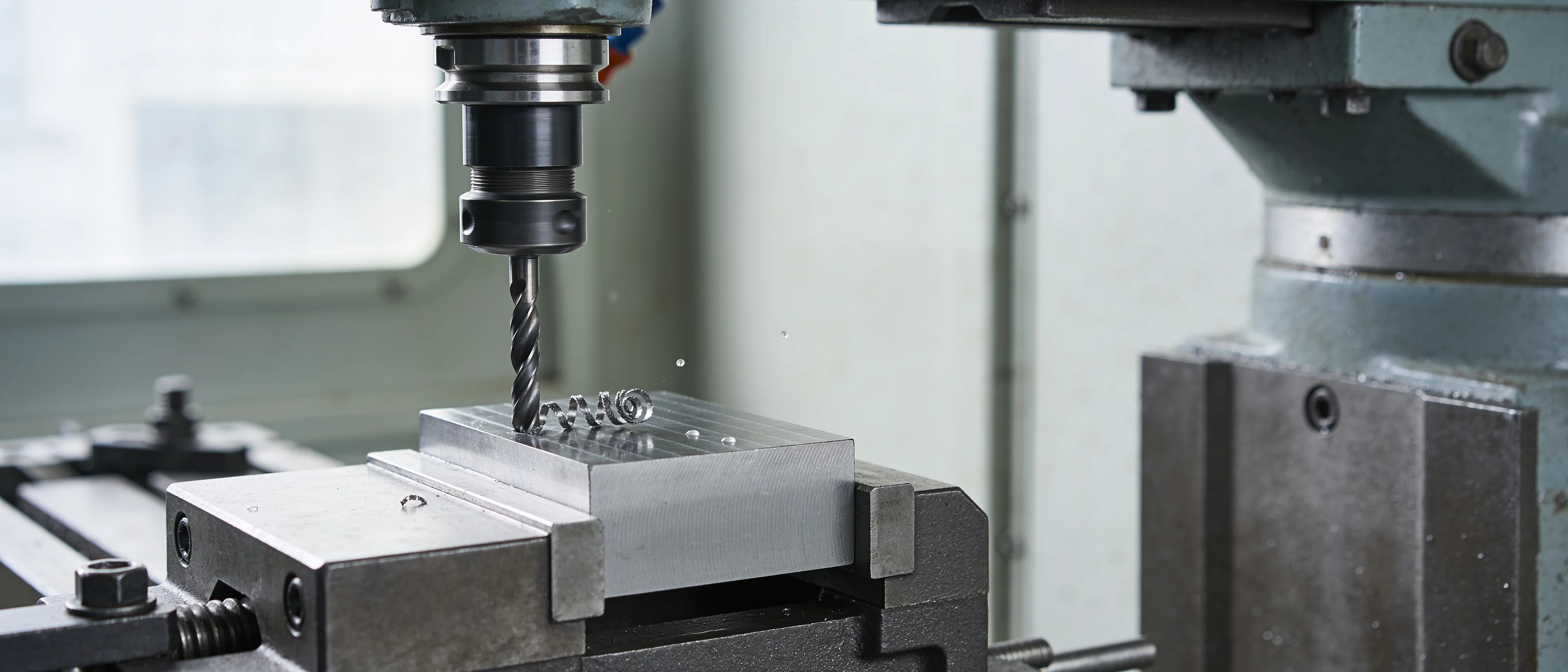 Spiralbohrer bohrt in einen eingespannten Metallblock