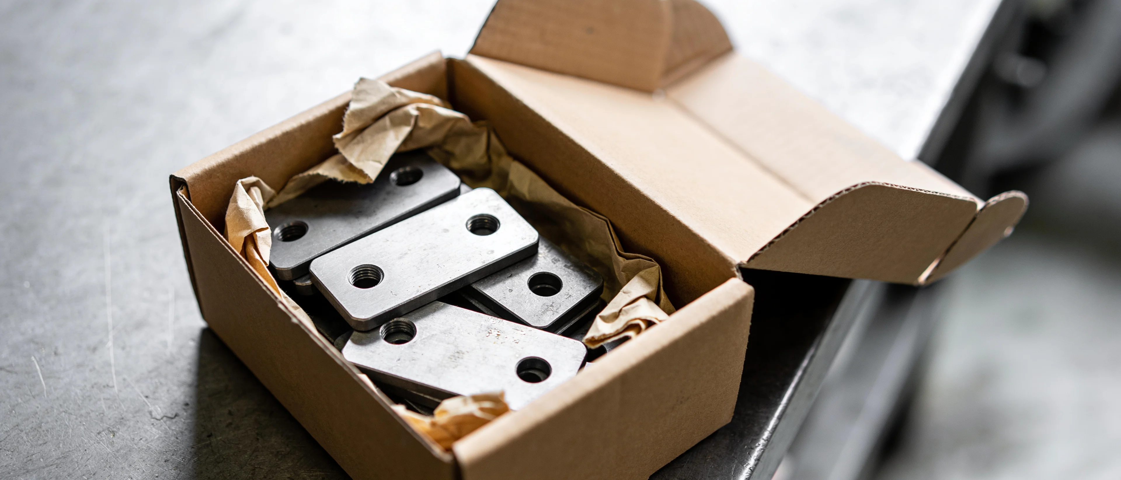Offener Karton mit Stanzteilen in Packpapier